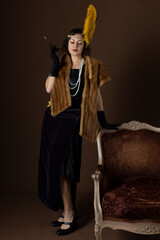 A 1920s woman wearing an evening dress and a fur stole and holding a cigarette in a long holder