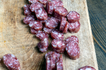 sliced thin sausage with bacon on a wooden dish