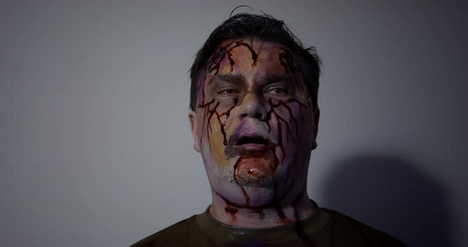 enraged hungry male zombie who sees the prey and wants to attack, looking around, blinking