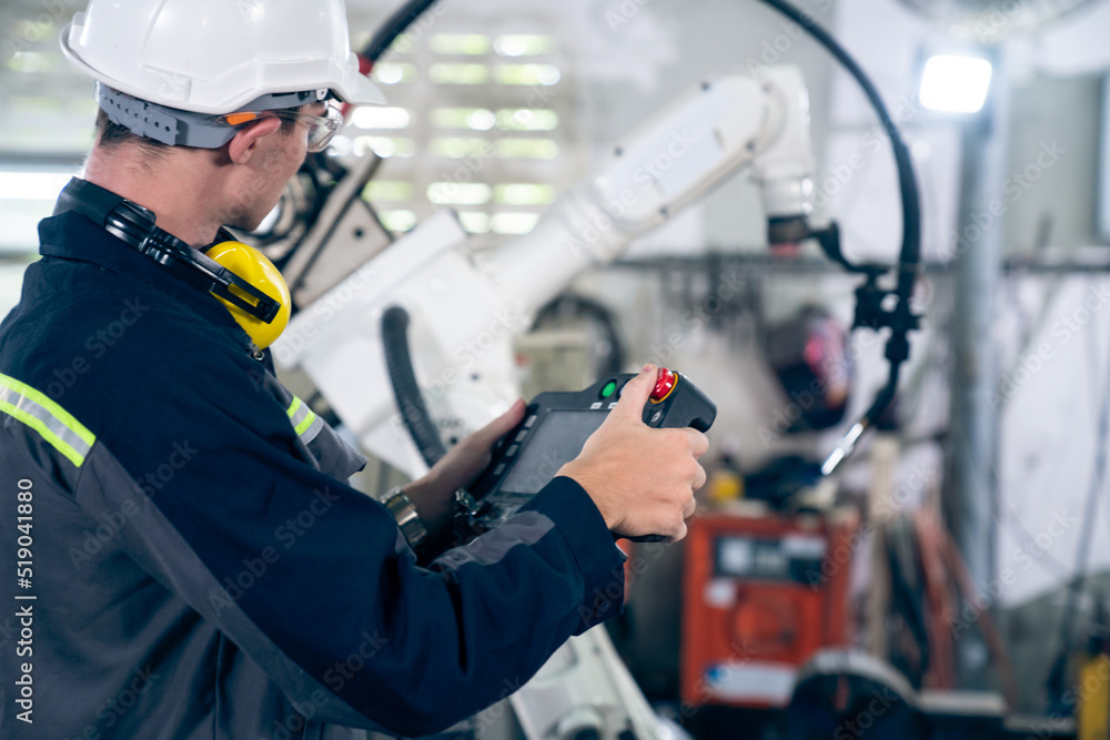 Poster young factory worker working with adept robotic arm in a workshop . industry robot programming softw
