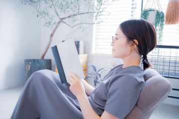 明るい室内で読書をする日本人女性