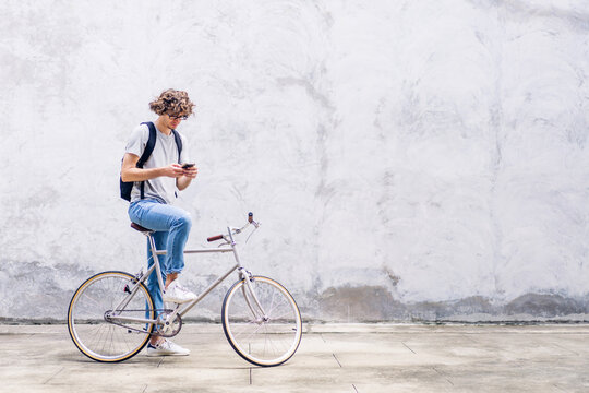 Portrait of casual hipster handsome businessman with backpack looking on smartphone while commuting riding bicycle on the street city way go to work.business travel transport bike concept