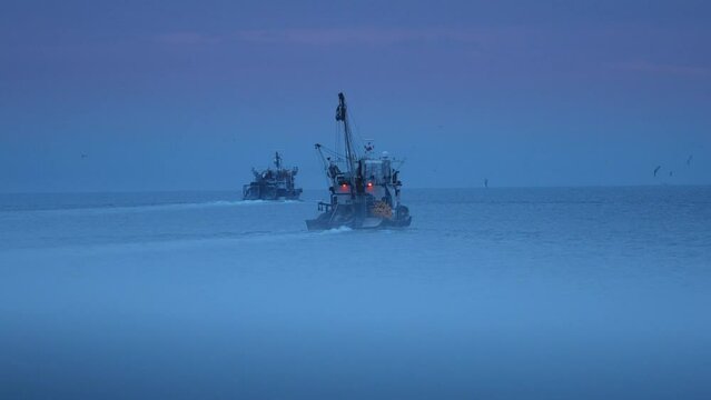 Two trawlers are sailing at dusk in Black Sea.