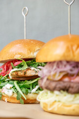 Grilled salmon burger with red onion, tomato and arugula and beef burger with cheese, onion, tomato and lettuce.