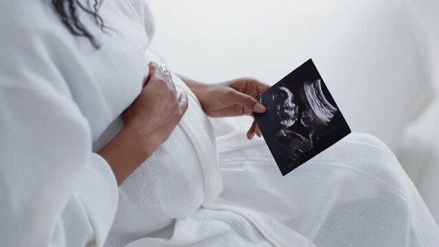 Maternity love. Close up shot of african american pregnant woman admiring sonography picture of her unborn baby