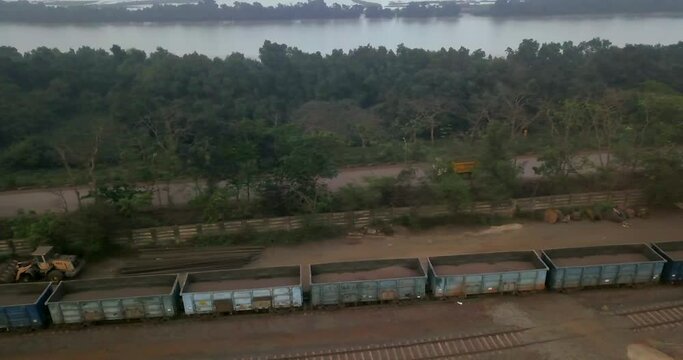 Dump Trucks Passing On Open Hopper Wagon On Railway At Paradip Port In India. - aerial