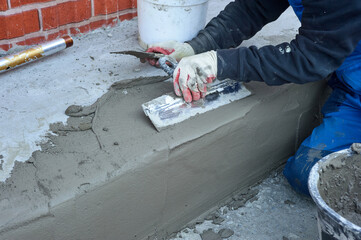 a worker uses a spatula to distribute the cement mixture along the ramp