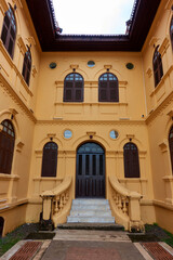 Fototapeta na wymiar The ancient yellow building colonial architecture There are beautiful decorative stucco components, doors and windows.