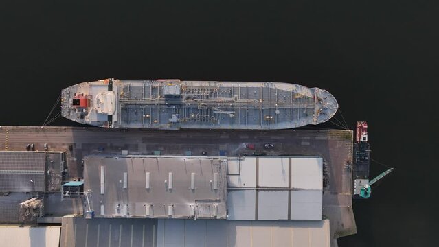 Petrochemical energy heavy transport industry cargo vessel tankers top down aerial drone view. Docked bulk carrier ship along storage facility silos. Energy gas and lpg petroleum commercial industry.