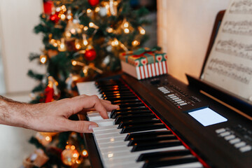 close up of many hands plays on Piano Keys with Christmas tree