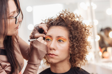 Make-up artist paints the eyelids bright colorin of model  in beauty salon