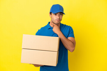 Delivery man over isolated yellow wall having doubts and thinking