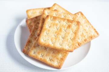 A pile of dry, thin crackers in a cup. Natural light.