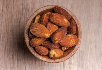 Salted almonds in a wooden cup. Healthy food concept, top view.