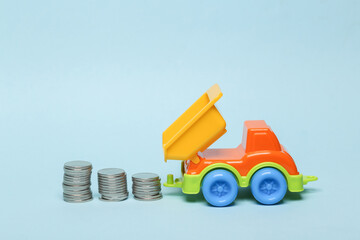 Truck with stack of coins on blue background