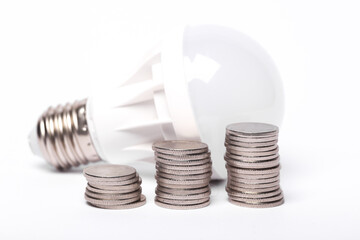 Saving money concept. Energy saving led light bulb with a stack of coins on white background