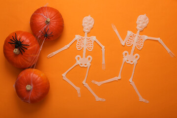 Halloween decor. Pumpkins with spiders, cobwebs and dancing skeletons on orange background. Flat...