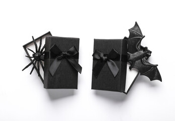 Black gift boxes with bat and spider on white background. Creative halloween layout. Top view. Flat lay