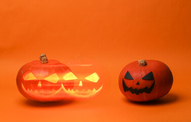 Halloween pumpkin head jack lantern with burning candles and phantom glow on orange background