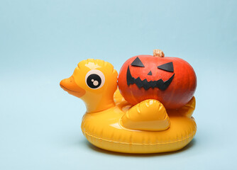 Halloween party. Halloween pumpkin with inflatable duck on blue background