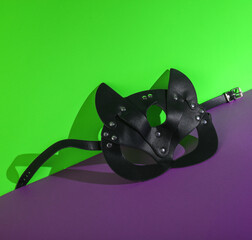 BDSM leather cat mask on a green-purple background. Creative layout