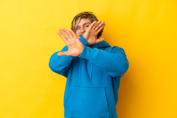 Handsome blonde man isolated on yellow background nervous stretching hands to the front