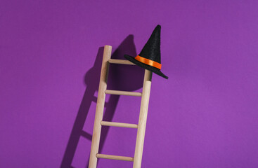 Wooden ladder with witch hat on purple background. Minimal halloween layout. © splitov27