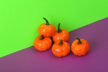 Halloween still life with plastic pumpkins on a green-purple background