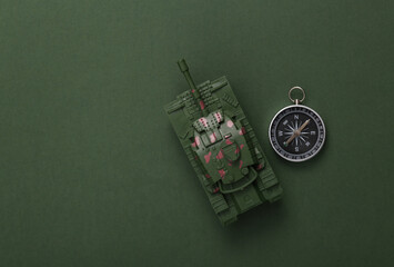 Plastic toy tank with compass on green background. Top view