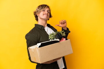 blonde man making a move while picking up a box full of things isolated on yellow background proud...