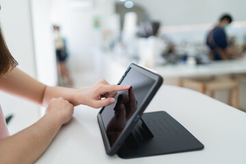 Woman hand touch screen on digital tablet while working in the coffee shop. Young girl works on the tablet on the internet, ipad surfing, woman using smartphone, holding tablet in hand