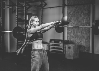 Fototapeta na wymiar Fit woman works out with heavy kettlebell in modern gym. Functional muscle training.