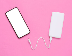 Smartphone and External portable battery (power bank) on pink background. Top view. Flat lay