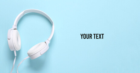 White stylish stereo headphones on a blue background. Minimalistic music still life, music lover. Top view. Flat lay