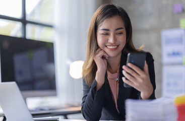 Business asian woman using mobile phone during checking an email or social media on internet working on laptop accounting financial concept.