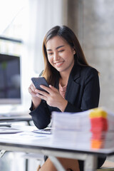 Business asian woman using mobile phone during checking an email or social media on internet working on laptop accounting financial concept.