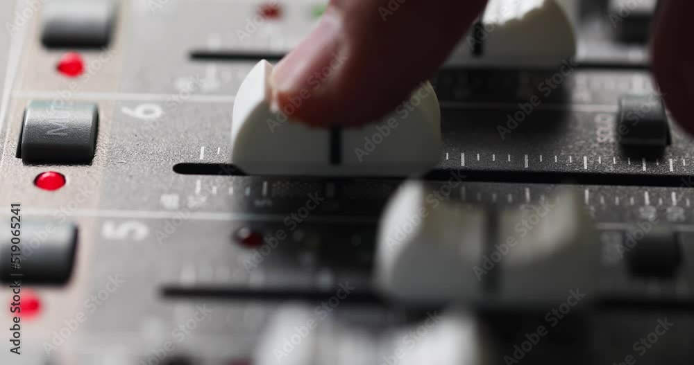 Poster mixing console, finger on channel fader gradually increasing and decreasing level of an audio signal