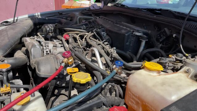 Refilling refrigerant in car with red and green tubes for air conditioning