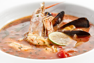 Tomato seafood soup in plate isolated on white background. Seafood stew Cioppino - shrimp,  mussels and salmon in tomato broth. Seafood dish in Italian restaurant menu.