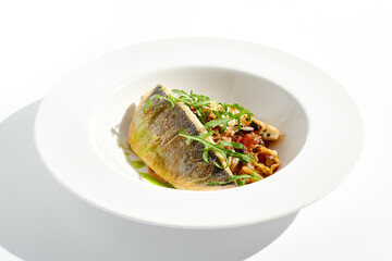 Roast white fish with vegetables isolated on white background. Grill halibut with crispy skin and tomato salad. Fish fillet with vegetables garnish in minimal style. Seafood Restaurant menu.