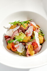 Roast beef and grilled vegetables salad isolated on white background. Steak salad with pastrami, eggplant, tomato, remoulade sauce with parmesan flakes. Gourmet dish  with grilled meat and vegetables.