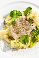 Roasted cod with mashed potatoes and broccoli. White fish fillet with skin with vegetables isolated on white background. Healthy food in restaurant menu. Fish and cabbages in minimalism style.