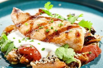 Healthy food - baked salmon steak with tomato salad and white sauce. Roast salmon with vegetables on contemporary plate in asian style. Restaurant dish - salmon filet with hard shadow.