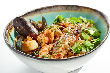 Japanese soba with seafood cooked on wok in asian style on white background. Noodle seafood in ceramic bowl. Indonesian wok with prawn, mussels and soba noodles. Spicy thai dish with shrimp and udon.