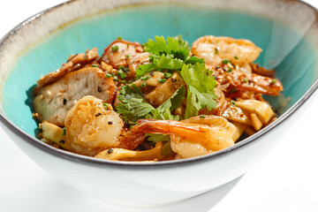 Pan asian food - udon with prawn, chicken wok on white background. Noodle with chicken and prawn in ceramic bowl. Indonesian wok with udon noodles. Spicy thai dish from noodle with shrimp and chicken.