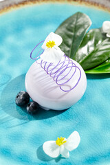 Blackberry mousse cake for concept design. Blueberry souffle with mirror glaze on ceramic plate. Mini cake with blackberry in restaurant menu. Summer sweet dessert - berries mousse with flowers.