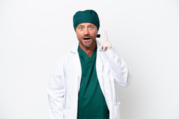 Middle age surgeon in green uniform isolated on white background thinking an idea pointing the finger up