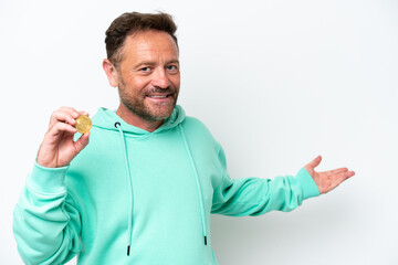 Fototapeta premium Middle age man holding a Bitcoin over isolated background extending hands to the side for inviting to come