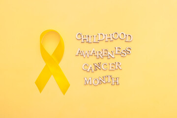 Childhood cancer awareness month text with ribbon on yellow background
