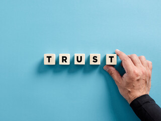 Male hand placing the wooden cubes with the word trust. Business trust